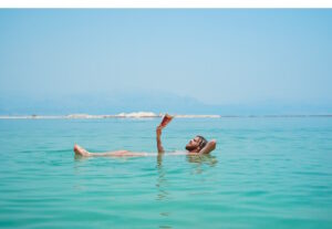 Relaxed man floating on his back in the sea while reading