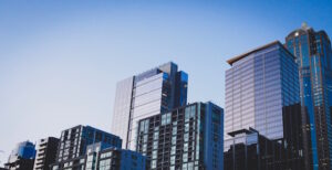 Several office buildings seen from a distance leaning up against blue sky