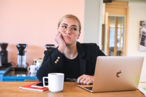 Bored woman sitting at computer, chin on her had looking away from screen