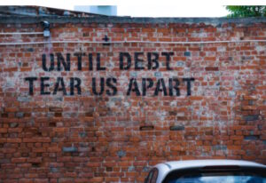 Until Debt Tear Us Apart written on a brick wall