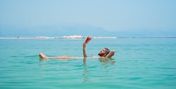 Man floating on Dead Sea while reading a book